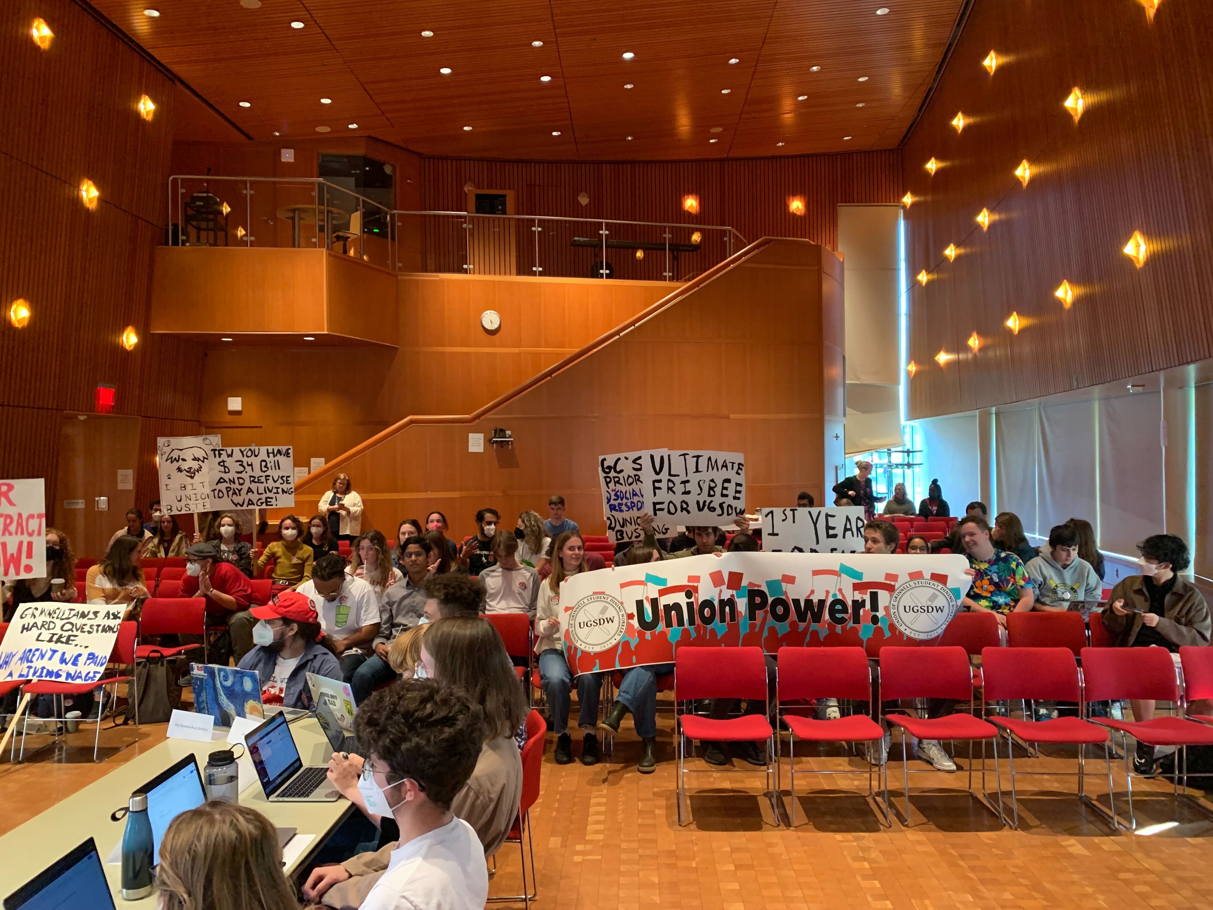 A photograph of the crowd observing the first bargaining session in JRC 101. They hold several pro-UGSDW signs, and most are wearing "UGSDW Fair Contract Now!" buttons.