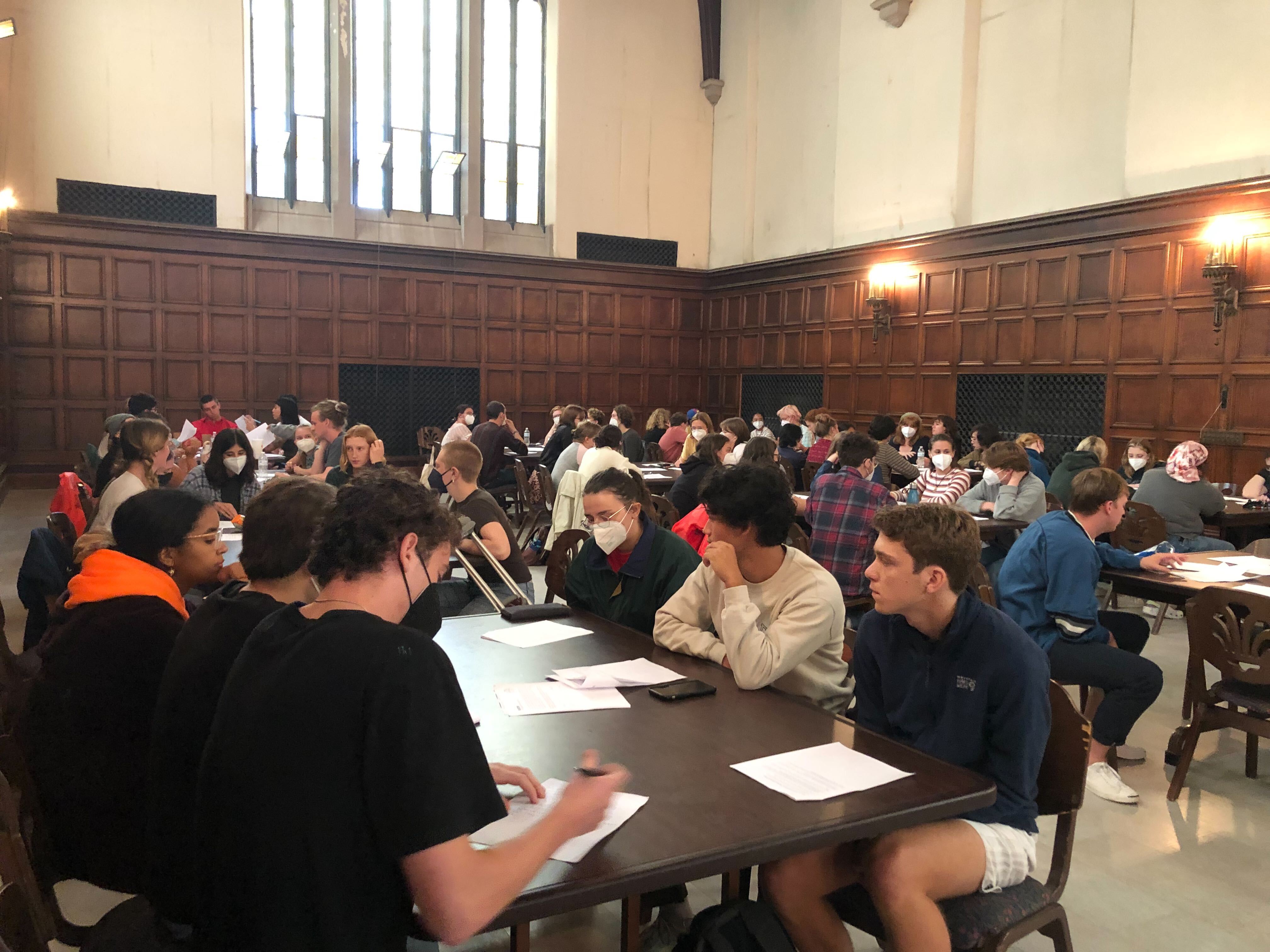 A photograph of many student-workers sitting at tables during the general meeting.